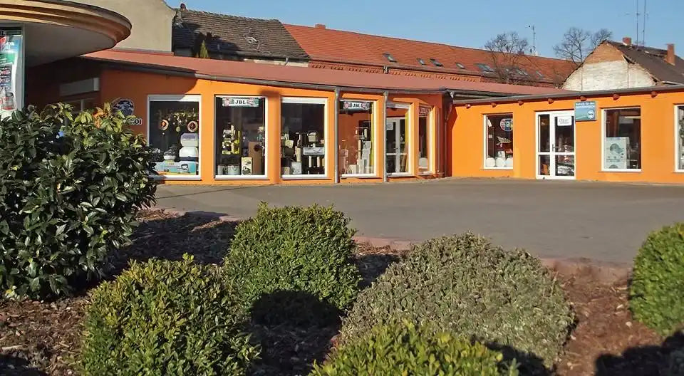 Ein orangefarbenes Geschäftsgebäude mit mehreren Ladenfronten und großen Schaufenstern.